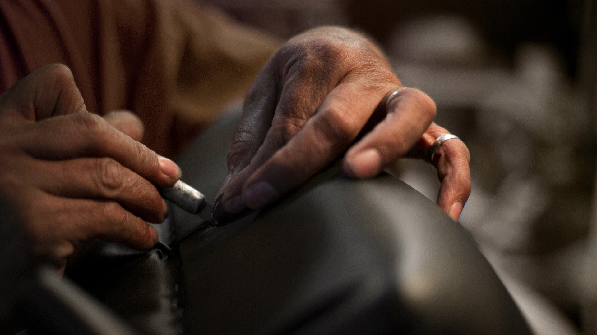 Man's hands cutting leather for P.L. Jansen artist bench